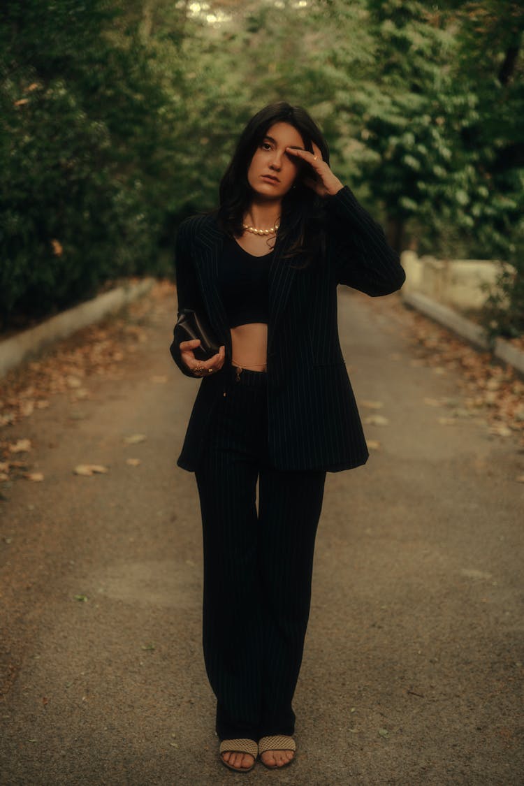 Woman In Pearls And Black Clothing Standing In Park