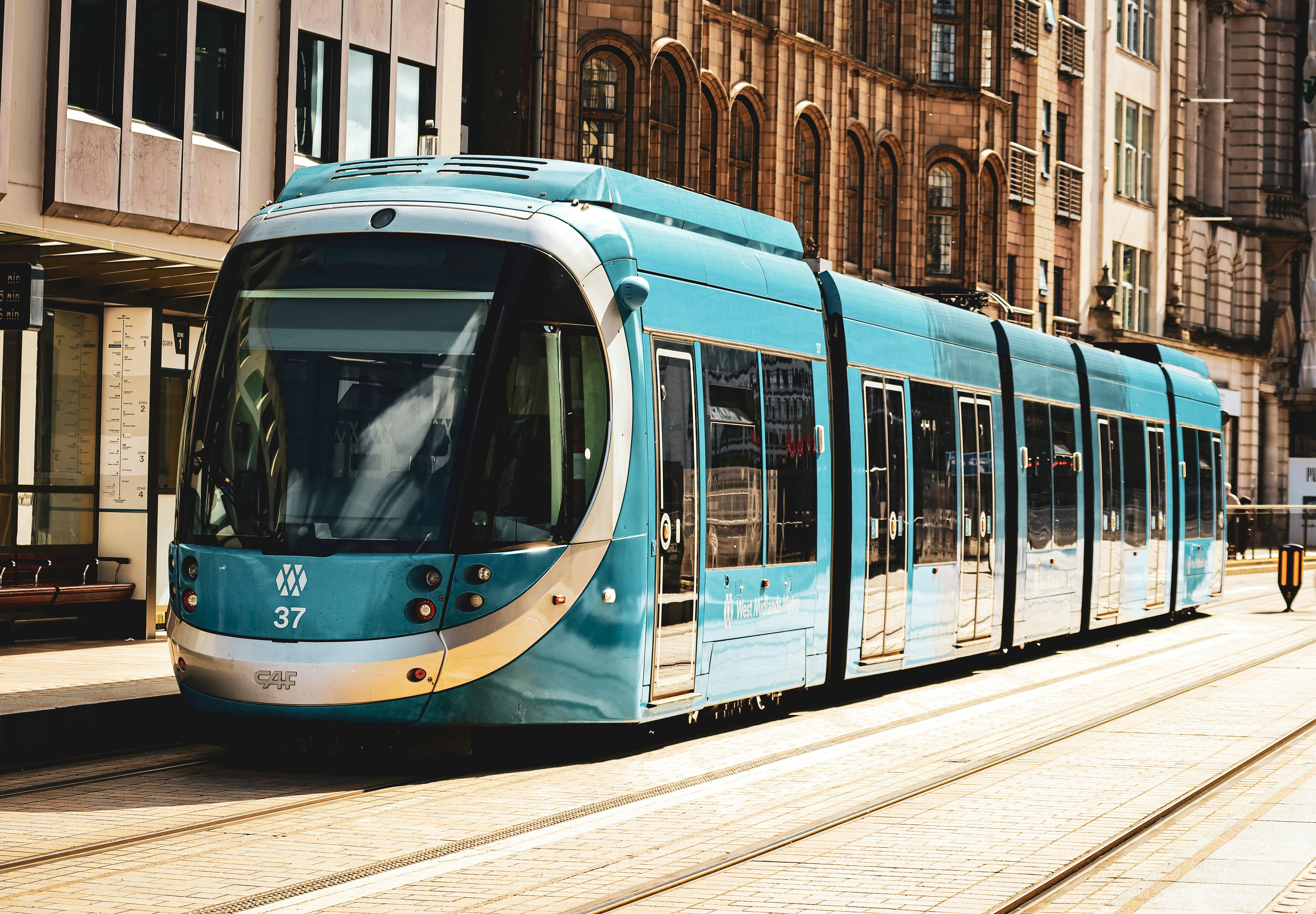 A vibrant blue tram on the streets of Birmingham, UK, showcasing urban transit.