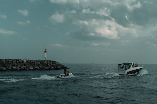 A boat is traveling through the water near a lighthouse