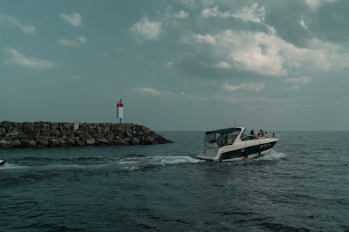 A boat traveling through the water near a lighthouse