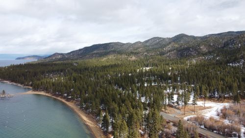 Free Scenic aerial view of snow-dusted forests and hills by the lakeshore in Zephyr Cove, Nevada. Stock Photo