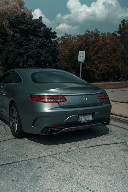 The back of a mercedes coupe parked on the side of the road