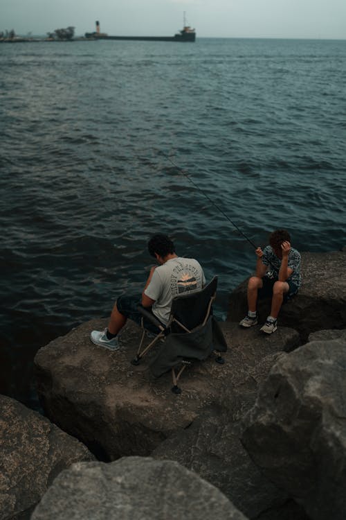 Two people sitting on rocks near the water