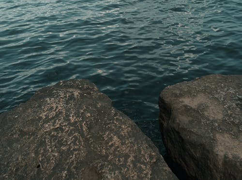 A body of water with rocks in the foreground