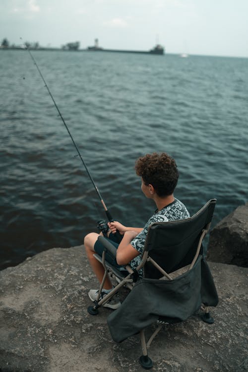 A man sitting in a chair on the edge of the water