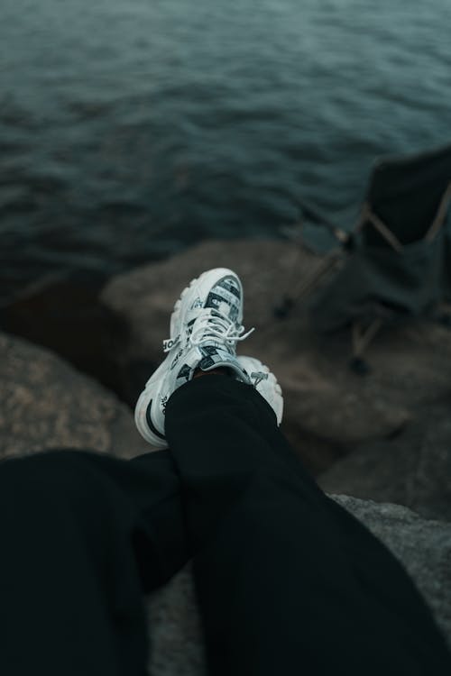 A person's feet on a rock near a lake