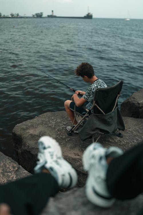 A person sitting on a chair next to the water