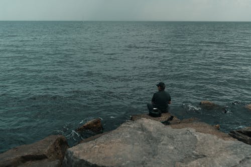 A man sitting on rocks looking out to the ocean