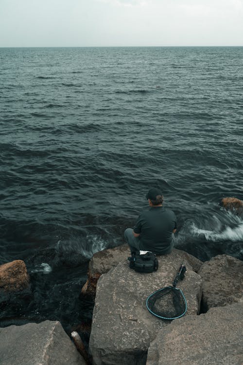 A man sitting on rocks looking out to the ocean