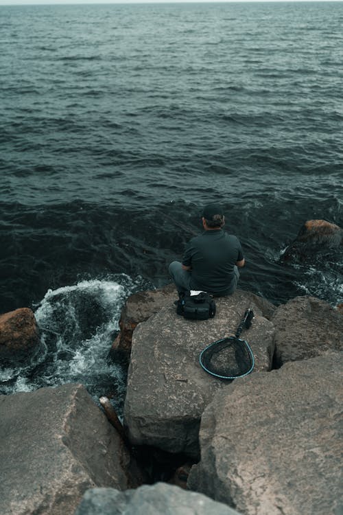 A man sitting on rocks looking out to the ocean