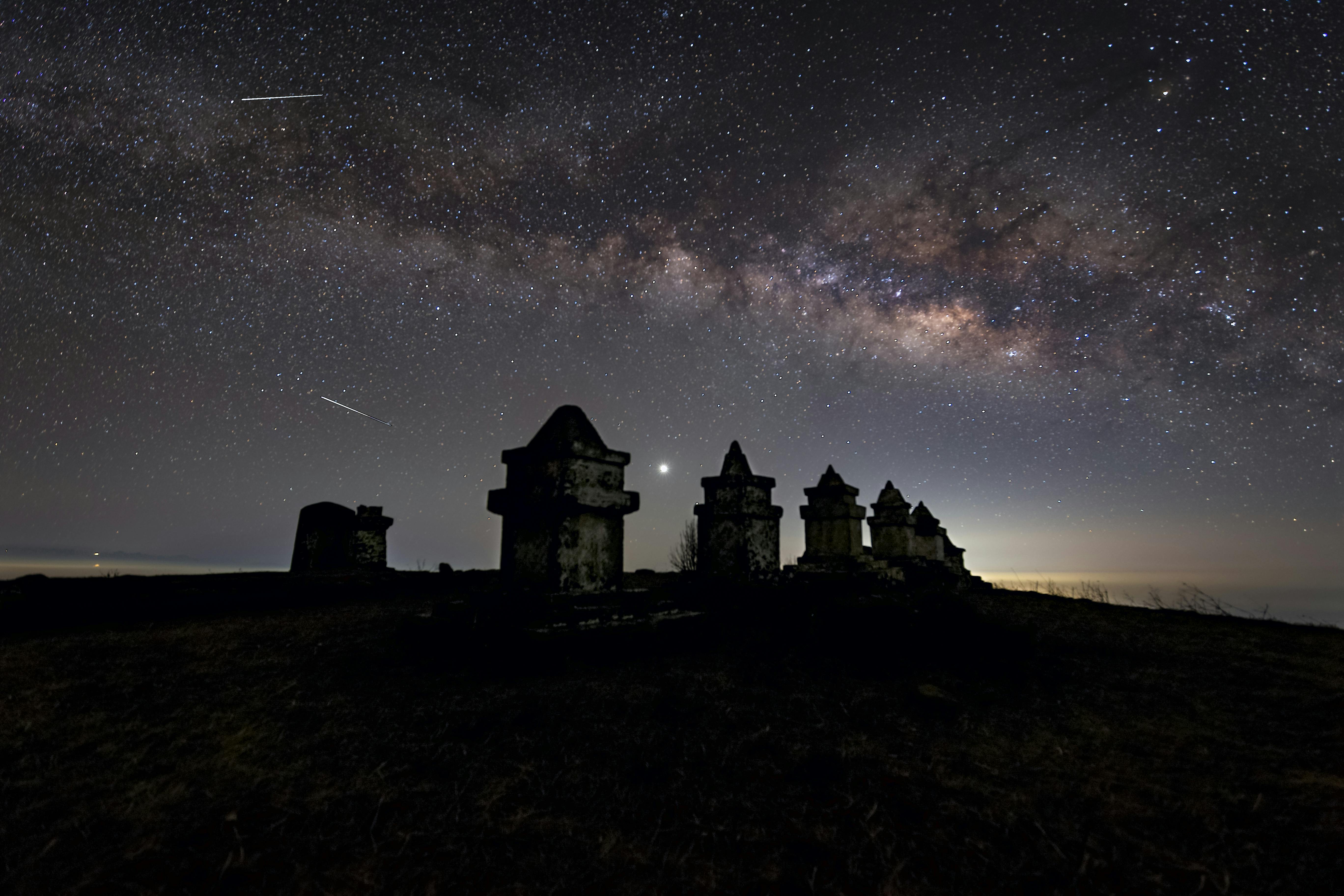 the milky way and some old buildings in the night sky