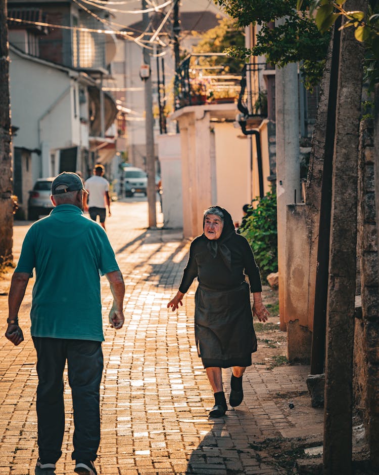 Elderly Woman And Man In Alley In Town