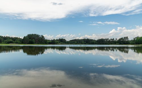 Free Peaceful lake scene with forest reflection, capturing calm nature and blue sky. Stock Photo