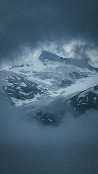 A dramatic aerial shot of Garibaldi's snowy peaks enveloped in mist under a stormy sky.
