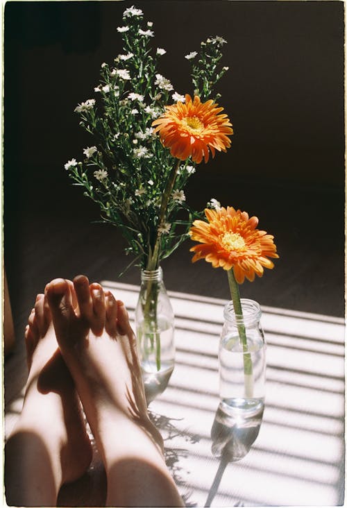 Feet near Flowers in Bottles