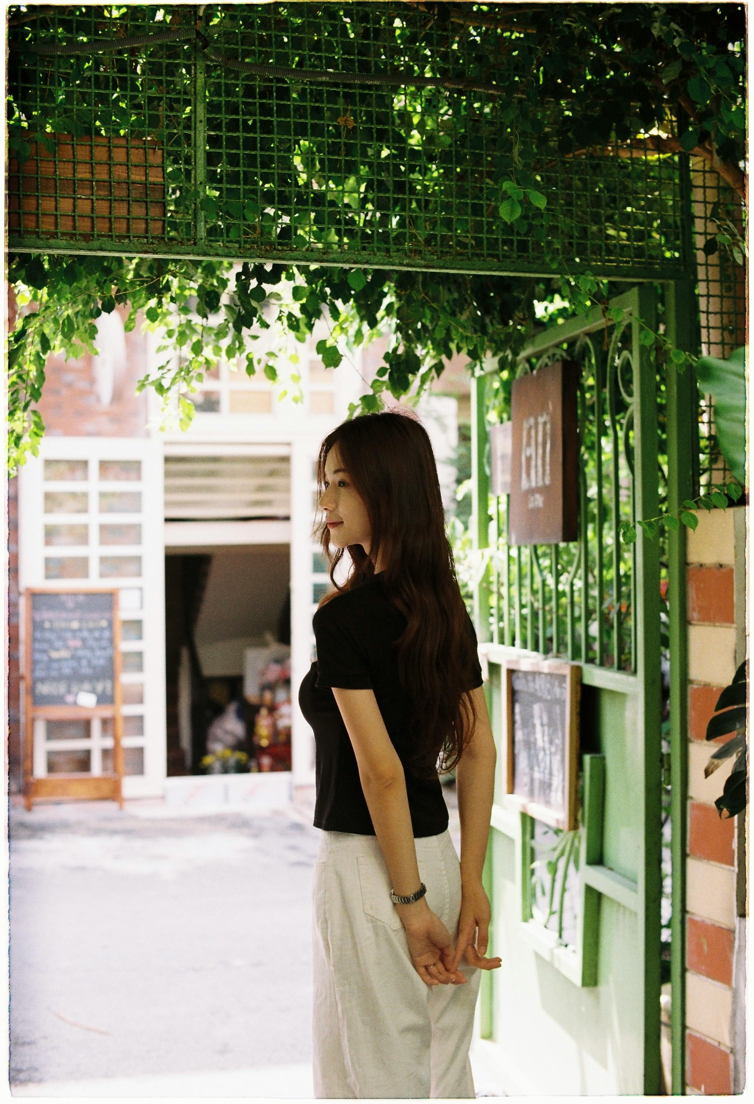 Elegant woman standing in a serene urban courtyard, showcasing modern fashion.