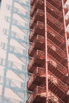 建筑立面上的红色防火梯投下阴影，展现出城市建筑的样貌