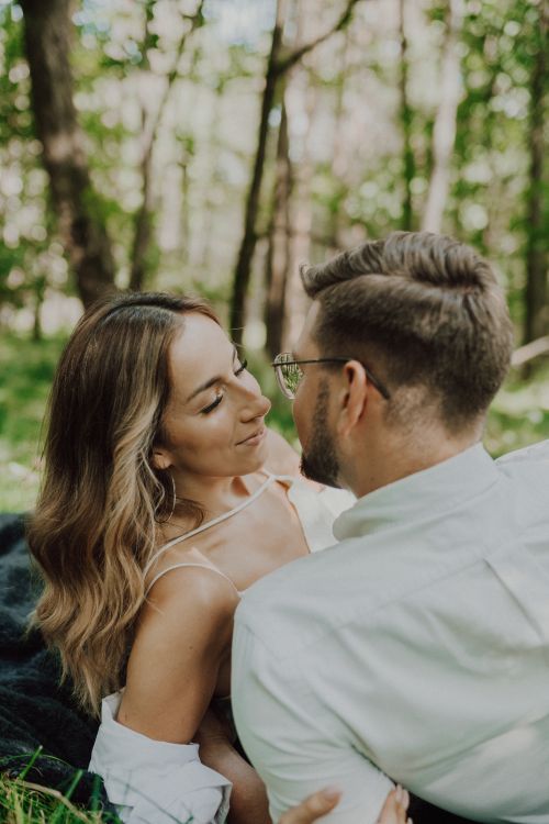 Free A loving couple shares a romantic moment lying together in a serene forest setting. Stock Photo
