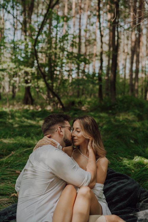 Free A couple sharing an intimate moment in a sunlit forest, epitomizing love and connection. Stock Photo