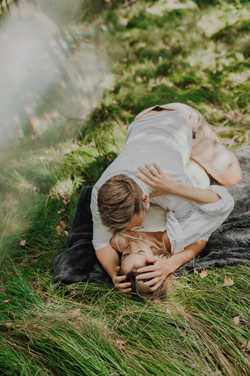 Free A couple lovingly embracing on grass in a serene outdoor setting. Stock Photo