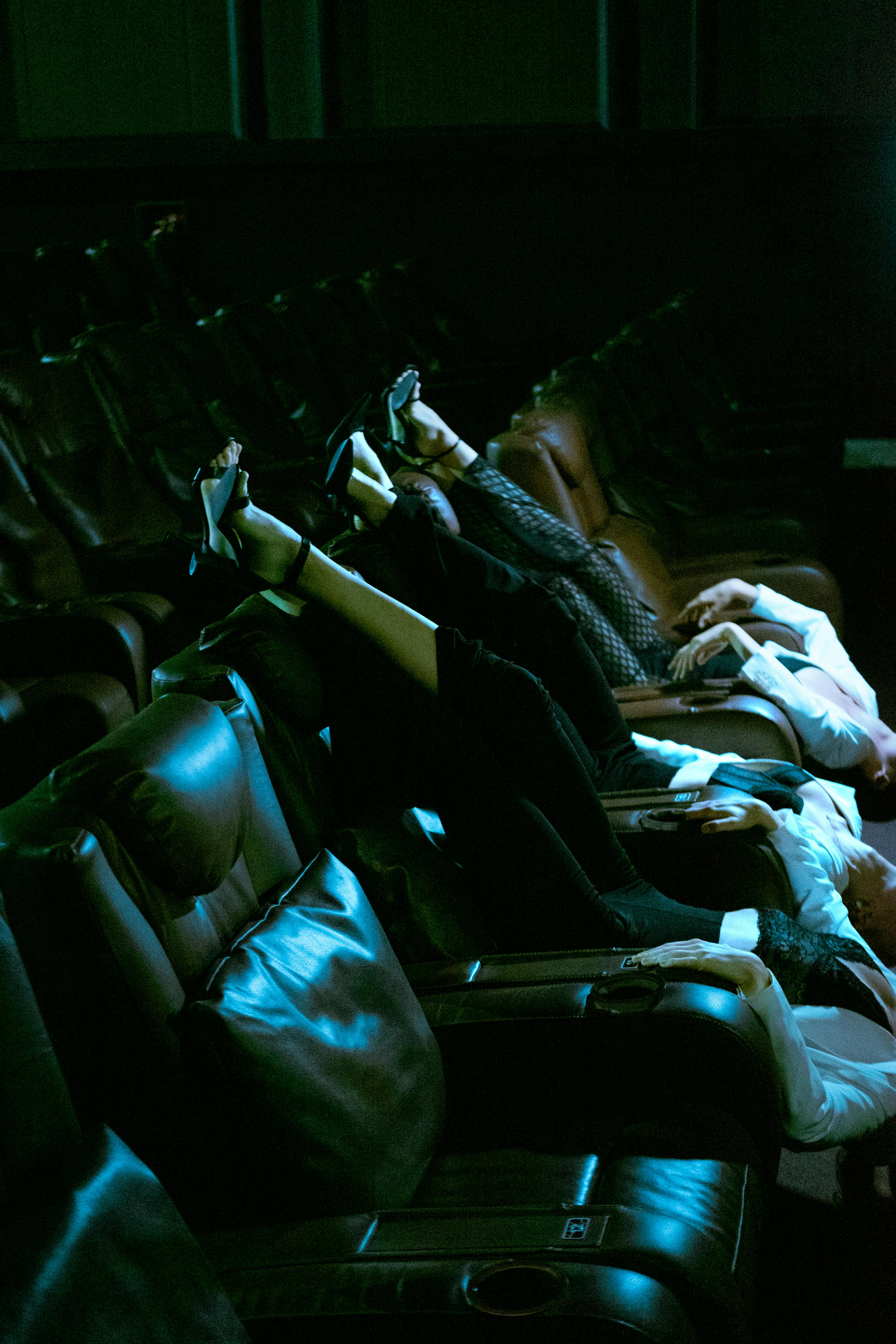 Free Women lying upside down on theater seats with legs raised, creating a unique visual scene. Stock Photo
