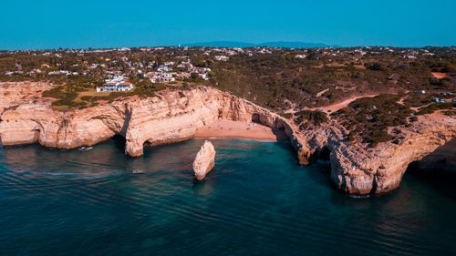 Free Breathtaking aerial shot of the rugged cliffs along a serene coastline during summer, highlighting clear turquoise waters. Stock Photo