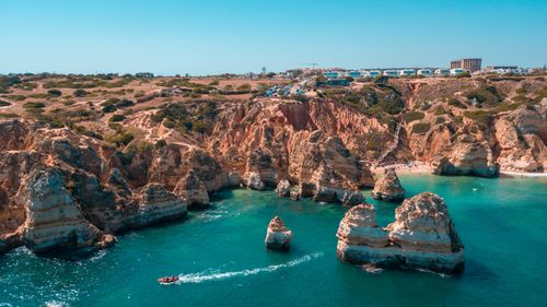 Free Stunning aerial shot of the rocky coastline in Lagos, Portugal's Algarve region, with clear blue sea. Stock Photo