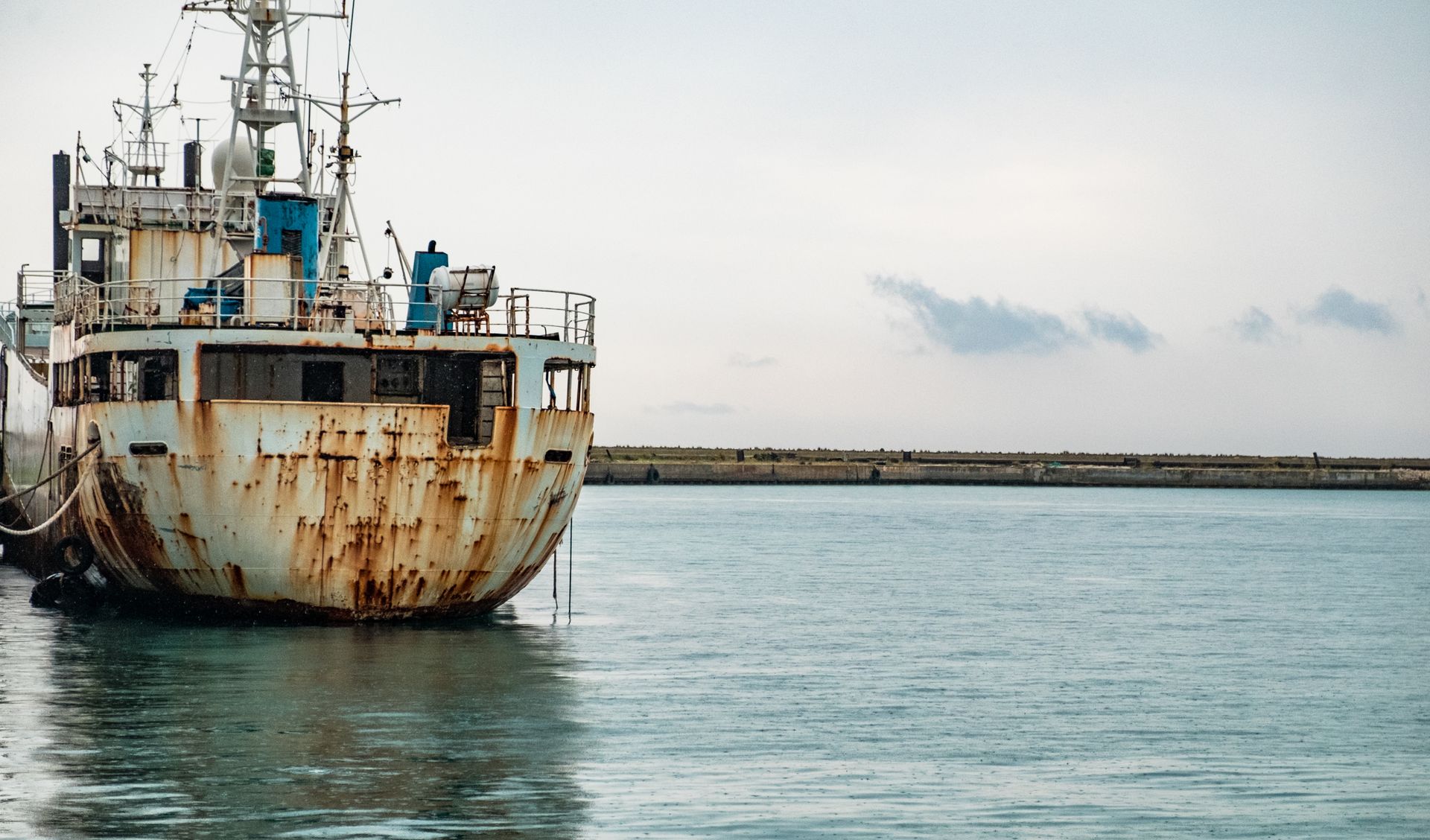 A weathered and rusty ship docked at sea, illustrating maritime industry decay.