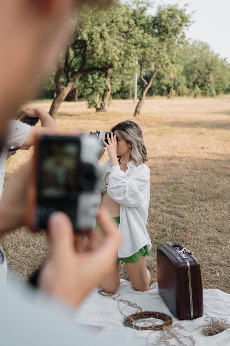 A Man Photographing A Woman With A Camera In The Park 