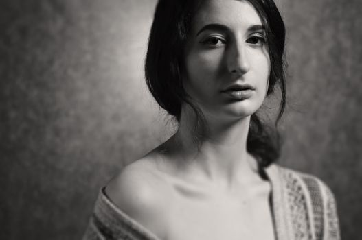 A woman in a sweater is posing for a black and white photo