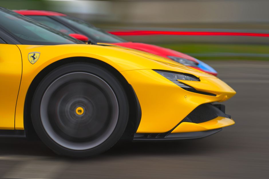 Close-up of a yellow Ferrari racing at high speed alongside a red car.