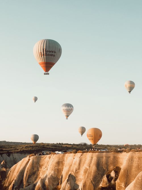 Free Hot air balloons float over the rocky landscape of Cappadocia, Turkey during a sunny day. Stock Photo