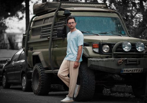 Free Man in casual attire leaning against a rugged military vehicle outdoors. Stock Photo