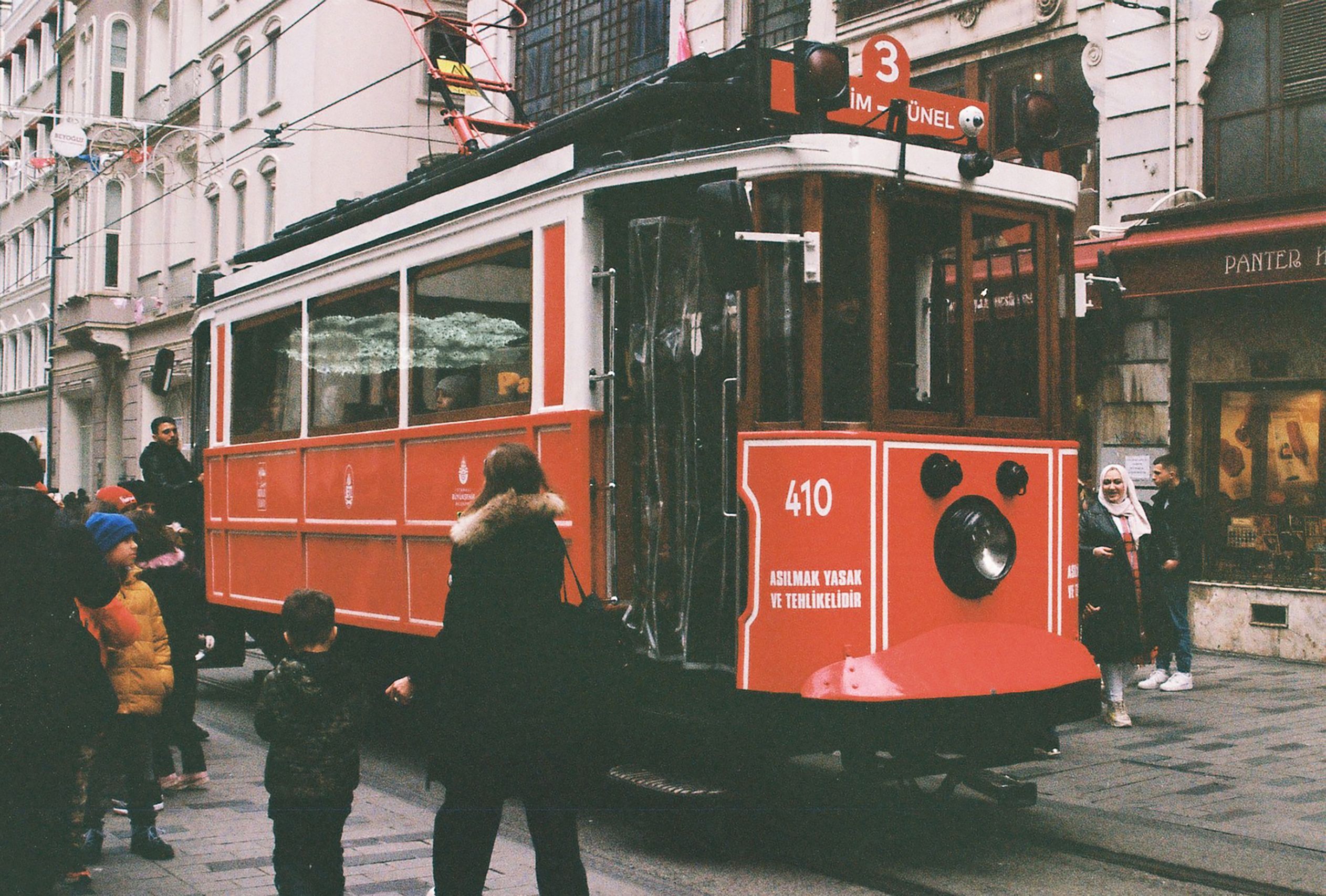 Capture of a classic red tram on İstiklal Street, bustling with people in Istanbul.
