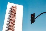 现代城市建筑立面下，蔚蓝的天空映衬着消防通道和红绿灯