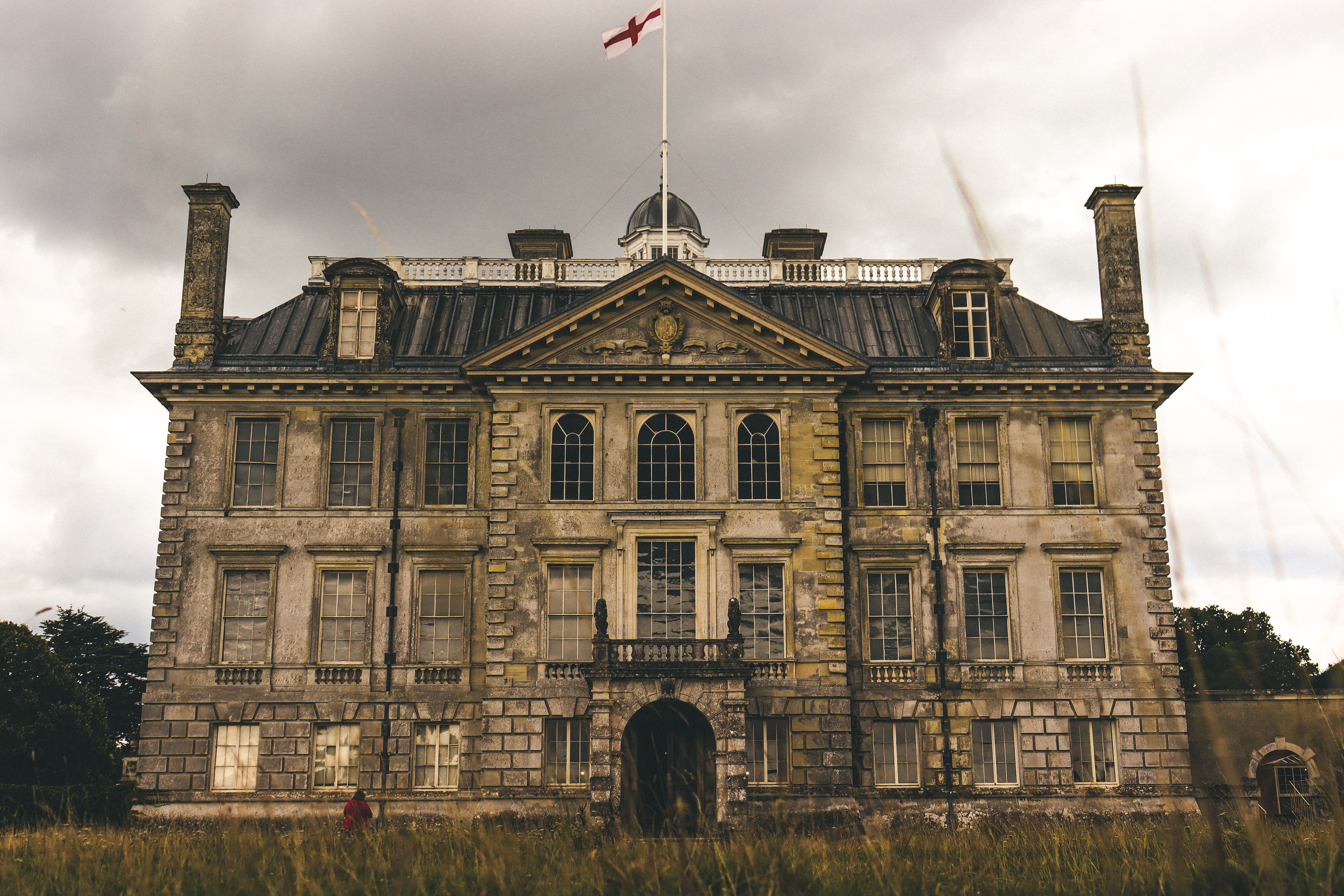 Front view of the historic Kingston Lacy manor house in England under a cloudy sky.