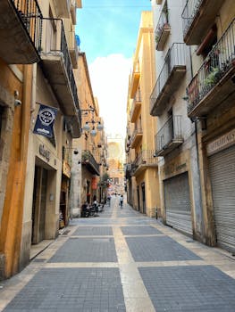 Explore a picturesque alley in Tarragona, Spain, lined with historic buildings and a lively urban vibe.