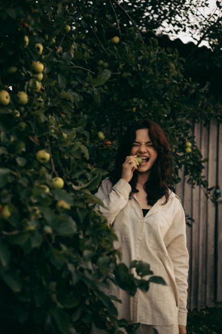 Young woman enjoying a fresh apple in a scenic Ukrainian orchard