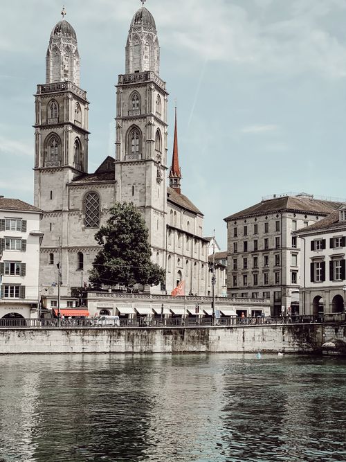 Free View of the iconic Grossmünster church in Zurich, Switzerland, with a river in the foreground. Stock Photo
