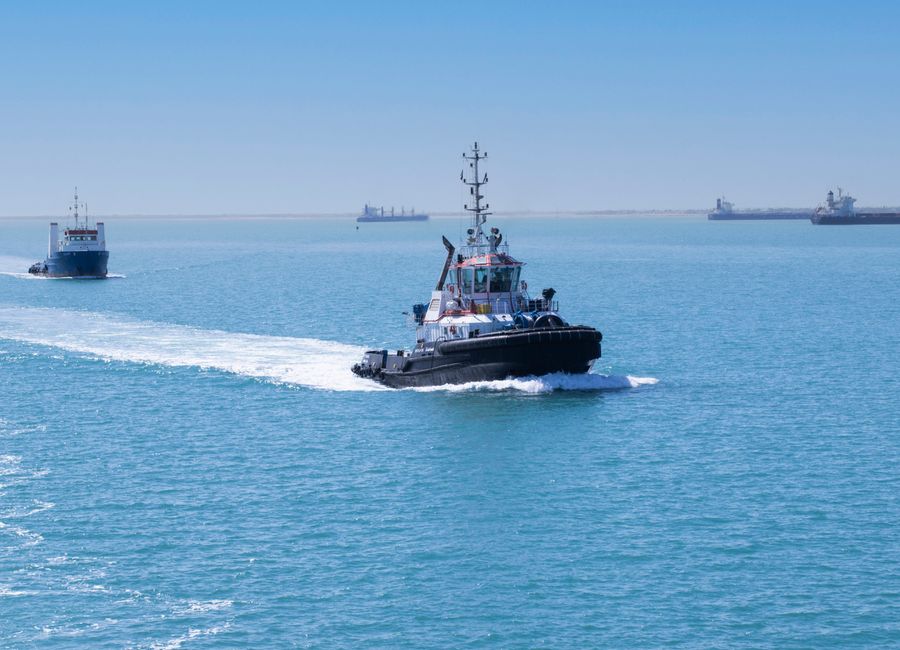 Tugboats navigating the Suez Canal in Egypt on a clear day, showcasing maritime activity.