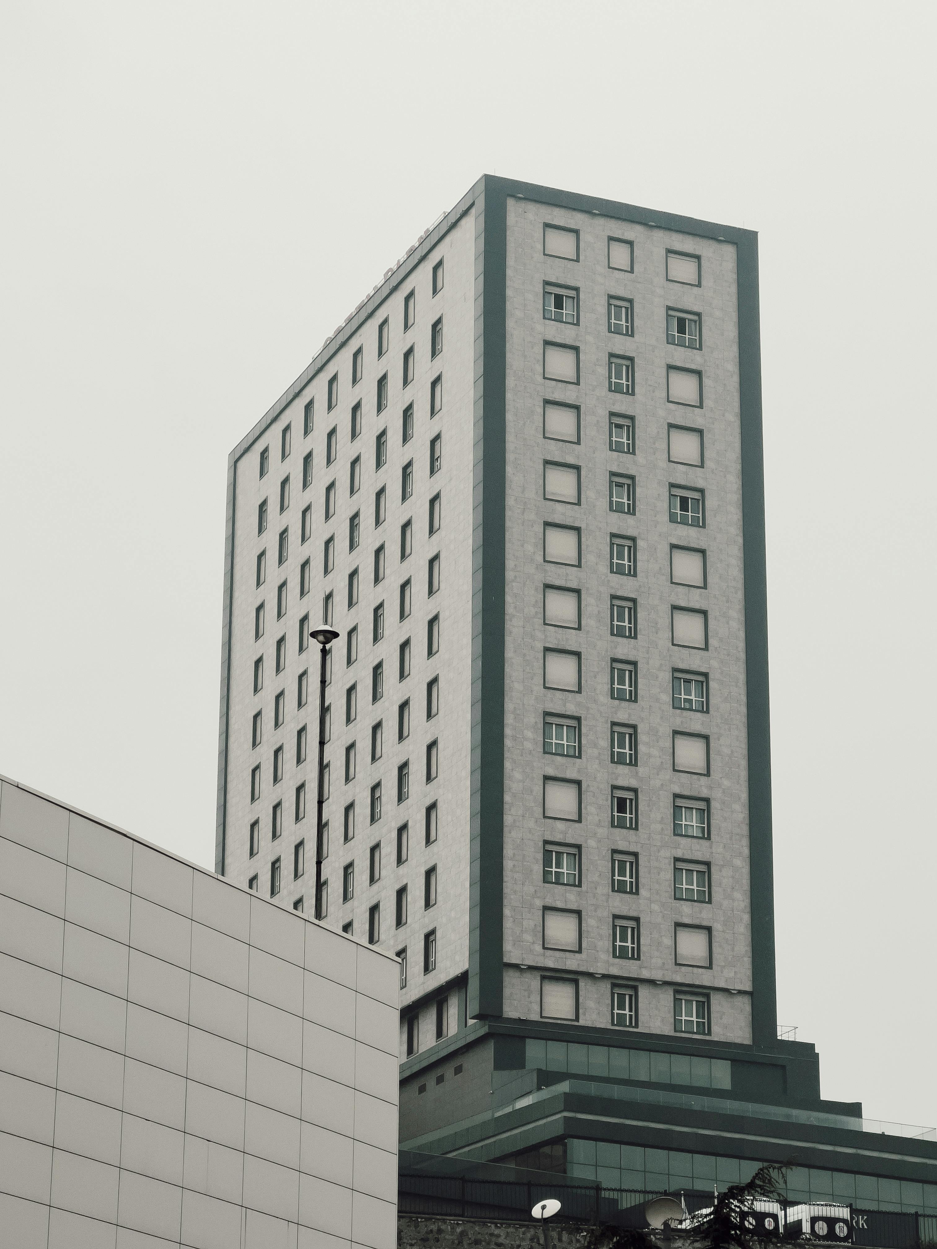 A minimalist vertical shot of a modern skyscraper with an overcast sky backdrop.