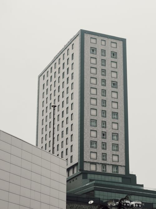Free A minimalist vertical shot of a modern skyscraper with an overcast sky backdrop. Stock Photo