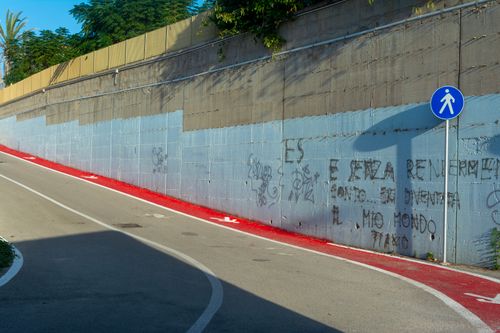 Free Urban environment featuring a bicycle and pedestrian lane beside a graffiti-covered wall. Stock Photo
