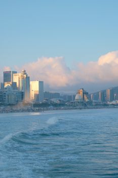Urban skyline with skyscrapers by the ocean at sunrise or sunset.
