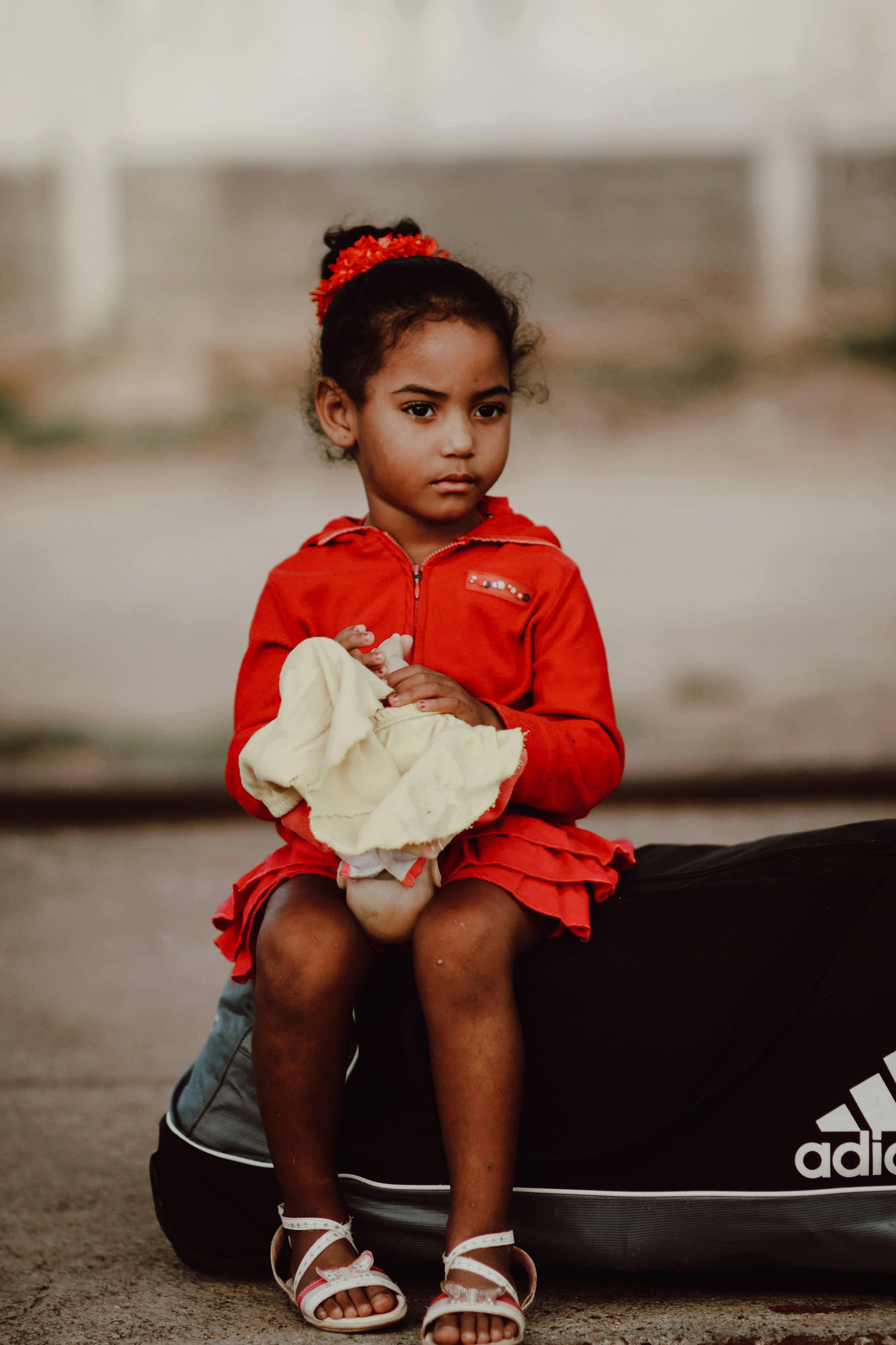 girl in red clothes sitting on sports bag