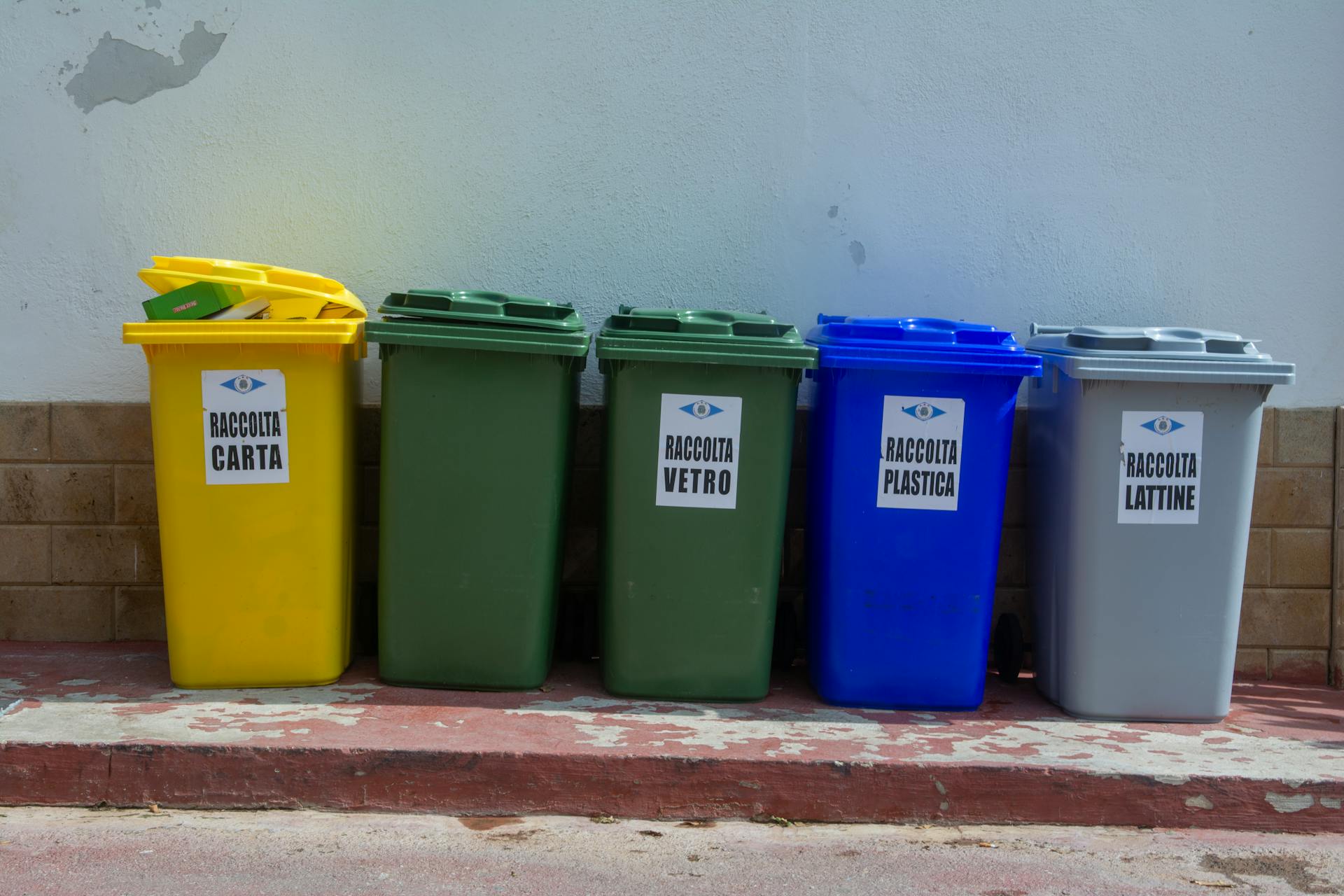 Five colorful recycling bins organized for waste segregation in an urban setting.