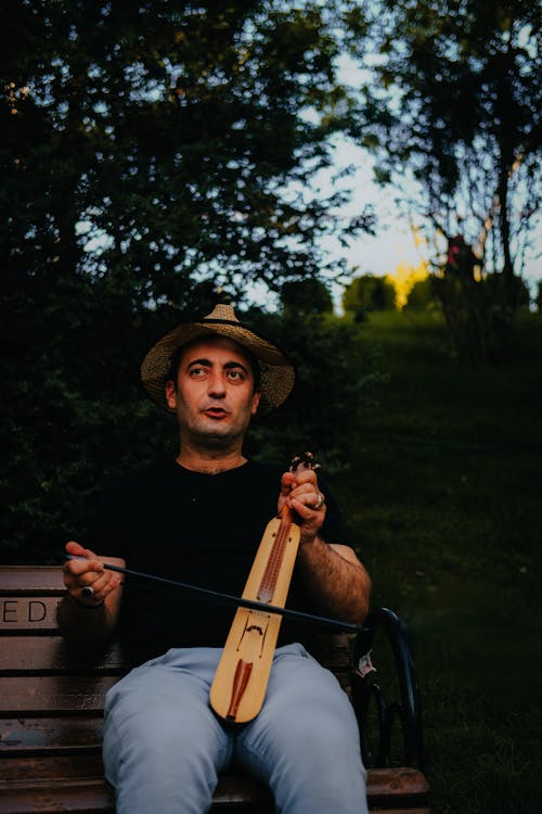 Man Sitting at Park and Playing Traditional Musical Instrument