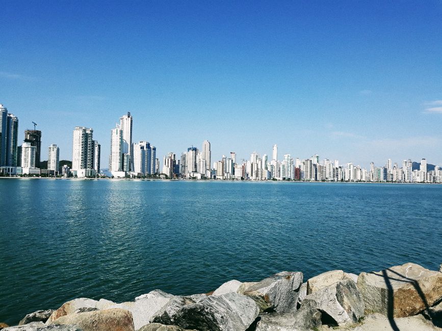 Picturesque cityscape of modern urban city with skyscrapers from stone embankment near rippled blue water