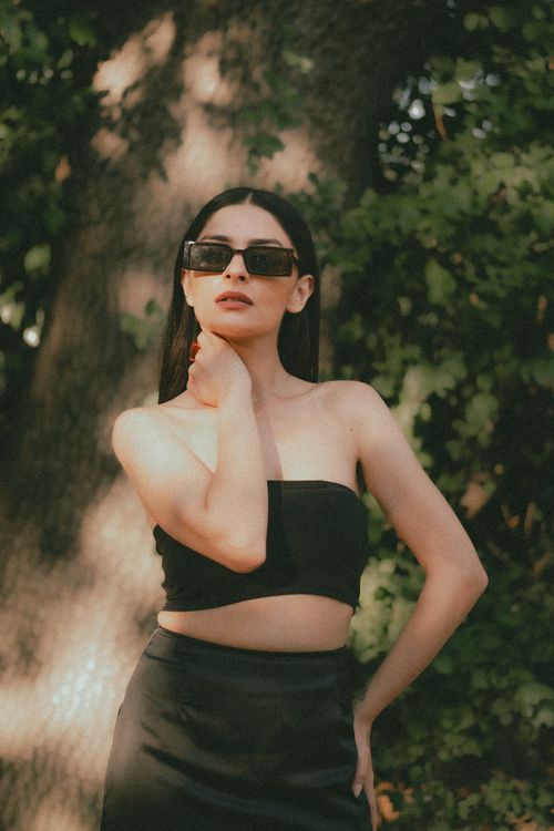 Free Stylish woman in black clothing and sunglasses in a sunlit forest setting. Stock Photo