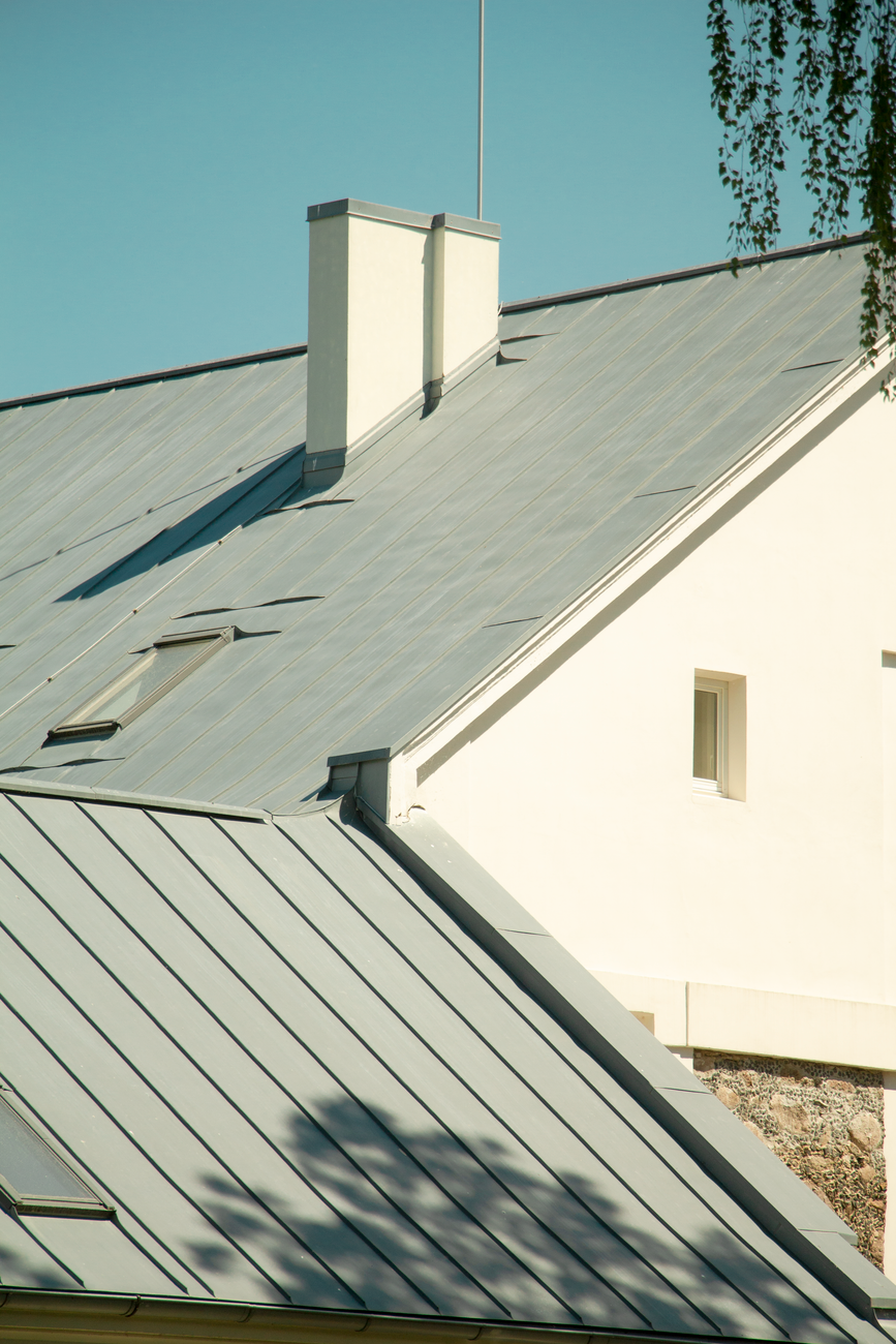 modern home with standing seam metal roof and white stone facade under clear blue sky